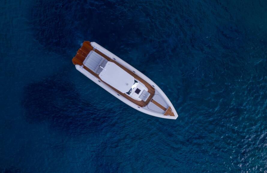 Top-down view of a luxury white speedboat floating on deep blue waters.